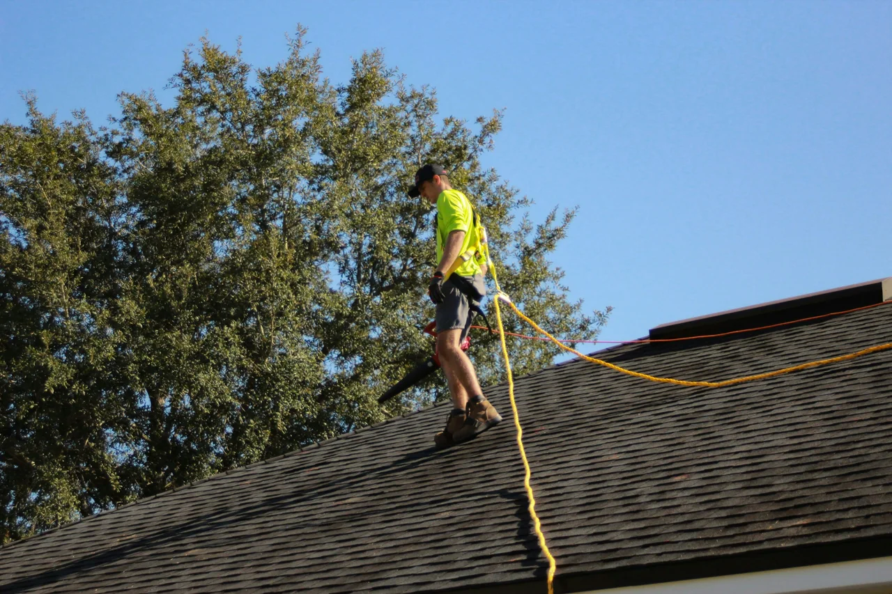 Roofer examining a pitched asphalt shingle roof